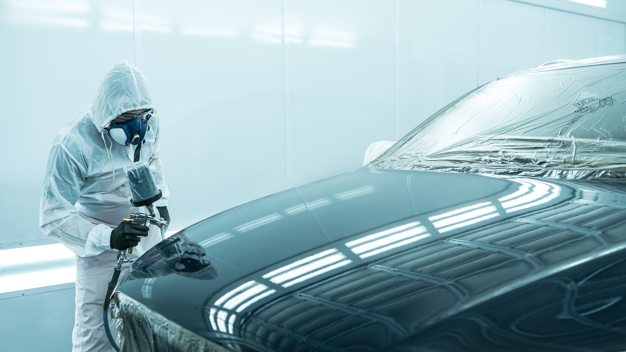 A man in overalls is about to paint a car.